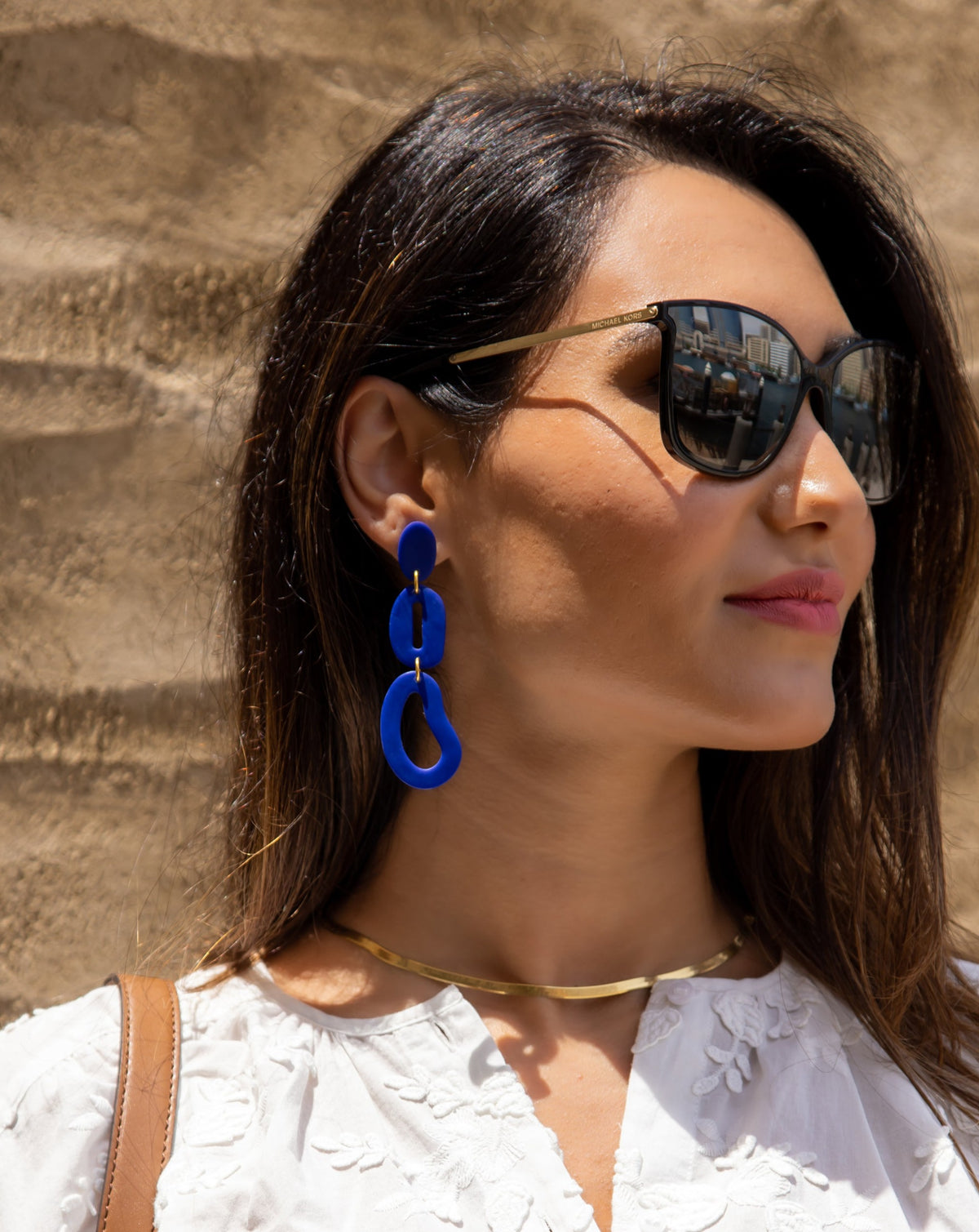 Abstract chain earrings in color blue on model.