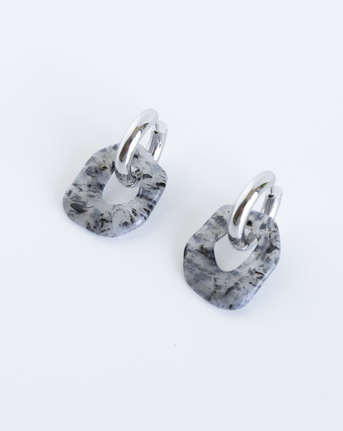 Darien earrings in black marble color with silver hoops, angled view