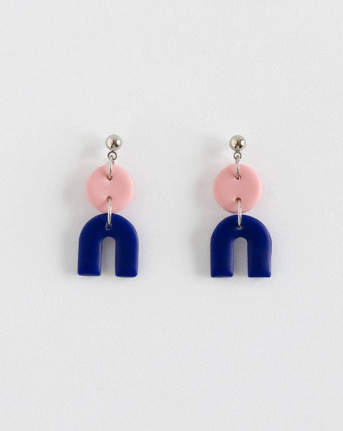 Tiny Arch earrings in two part of Sof pink and Hue Blue polymer clay parts with silver Ball studs, front view.