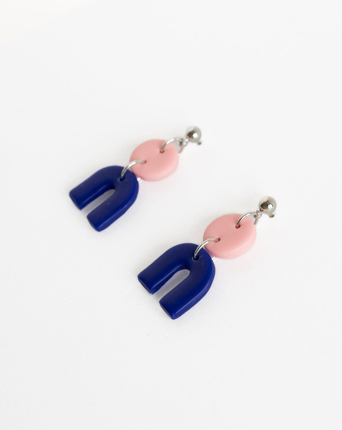 Tiny Arch earrings in two part of Sof pink and Hue Blue polymer clay parts with silver Ball studs, angled view.