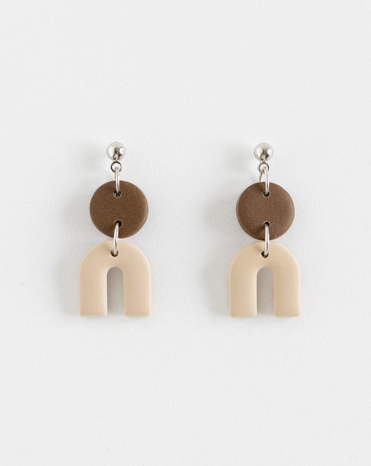 Tiny Arch earrings in two part of brown and beige clay parts with silver Ball studs, front view.