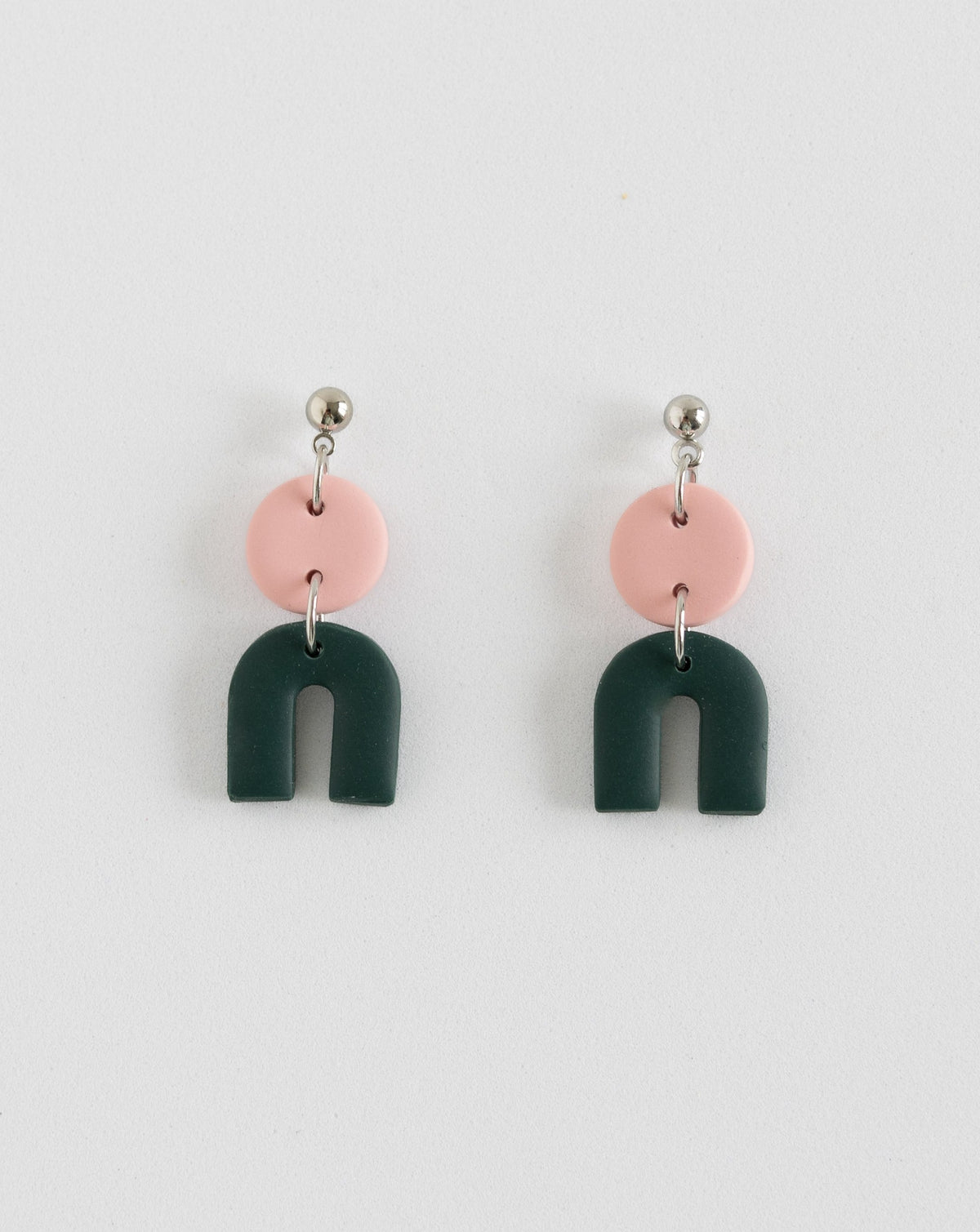 Tiny Arch earrings in two part of pink and pine  clay parts with silver Ball studs, front view.