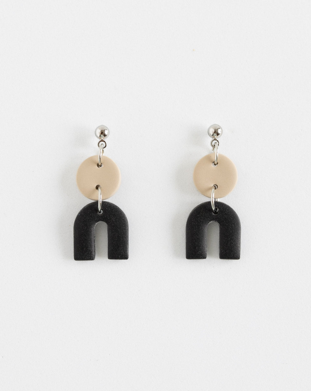 Tiny Arch earrings in two part of Beige and black clay parts with silver Ball studs, front view.