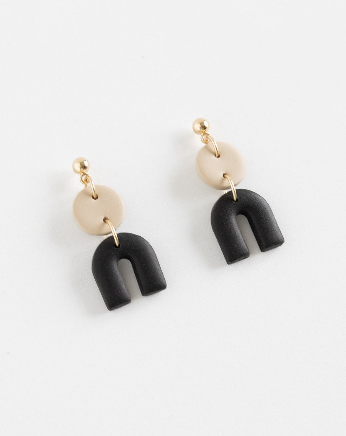 Tiny Arch earrings in two part of Beige and black clay parts with gold plated Ball studs, angled view.