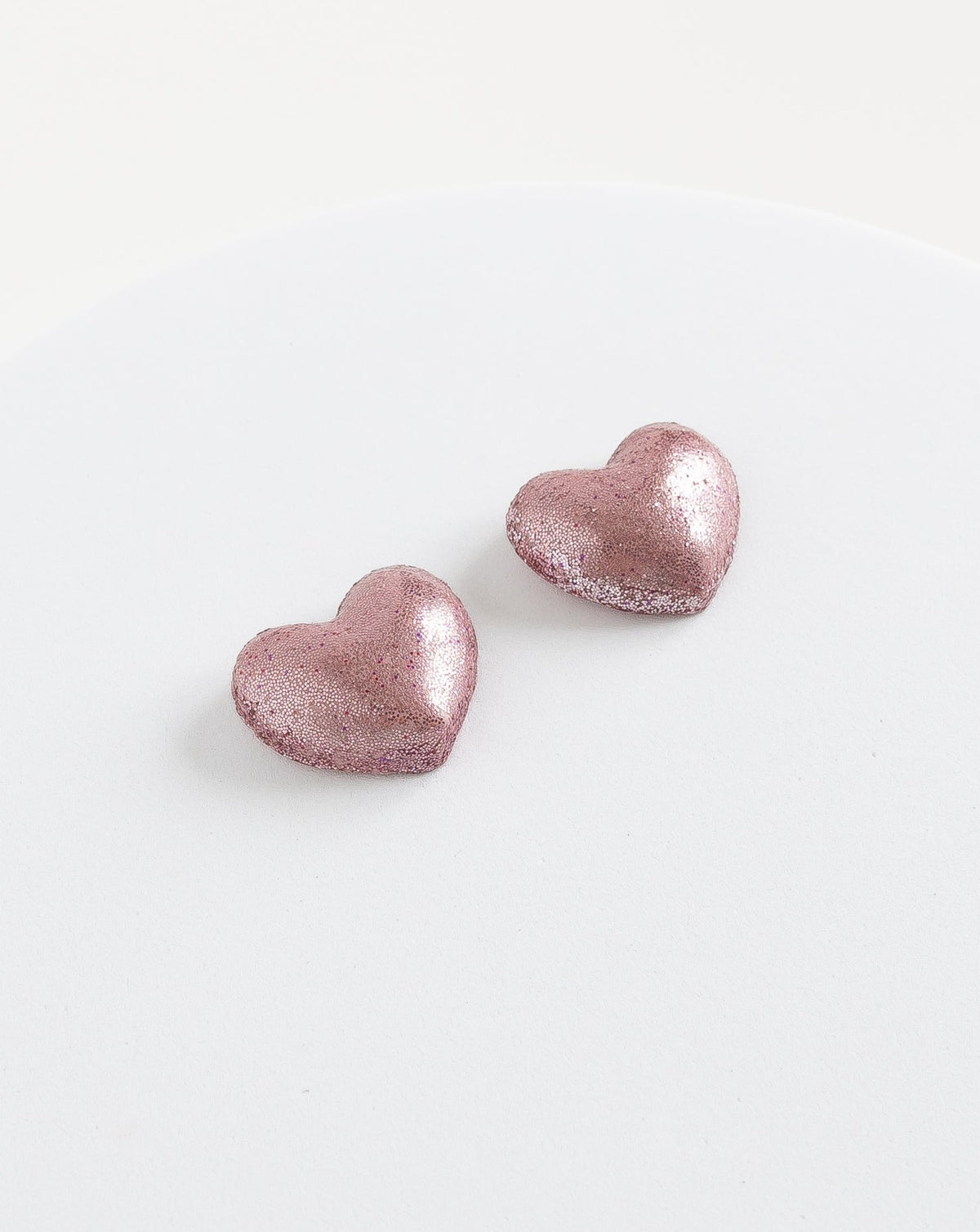 angled view of Heart stud earrings in color pink. they are handmade in the Netherlands by LYHO studio.