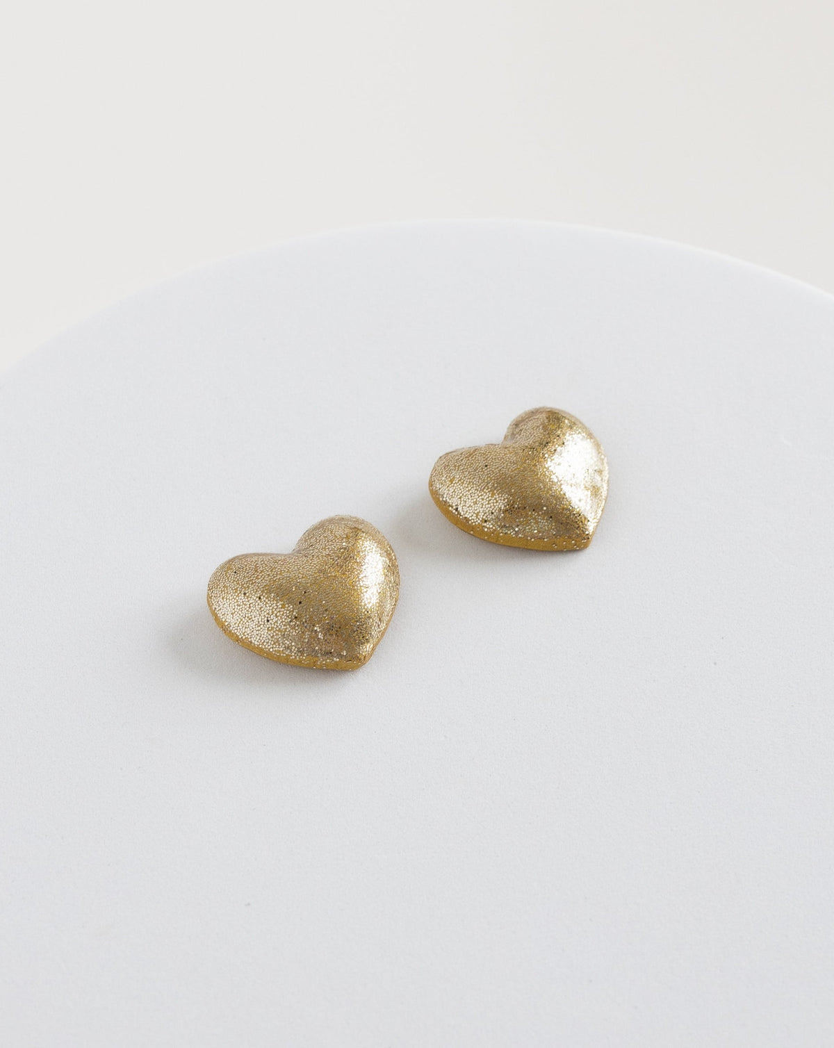 angled view of heart stud earring in color gold.