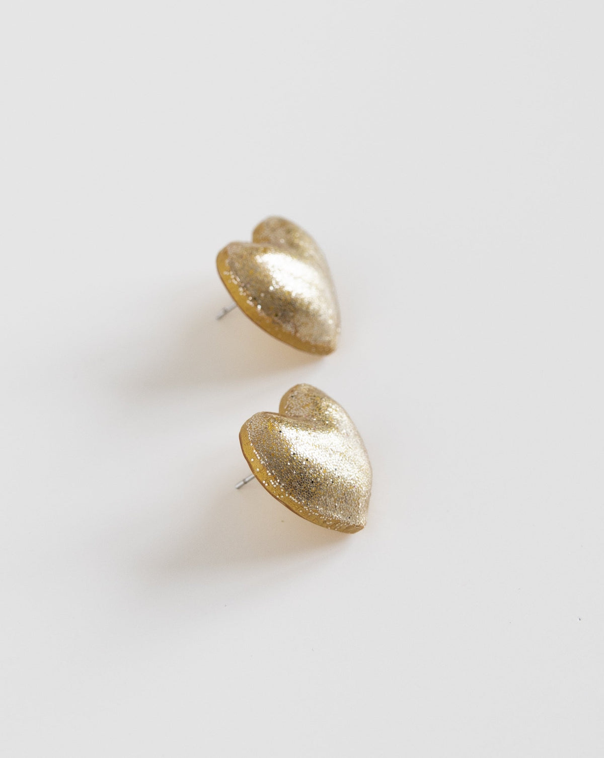 Close-up of LYHO&#39;s handmade polymer clay heart stud earrings in shimmering Gold.