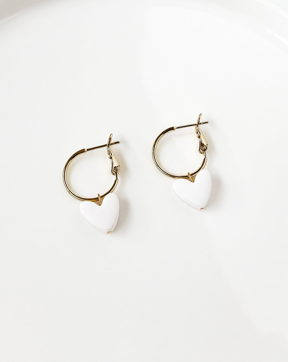 Close up of Charming Heart earrings with Gold Regular Hoops and white Heart charm.