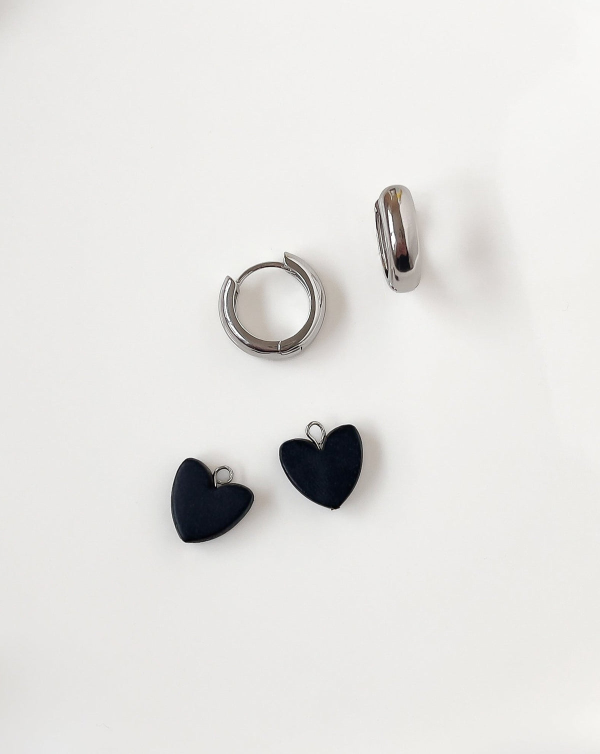 Close up of Charming Heart earrings with Bold silver Hoops and black Heart charm.