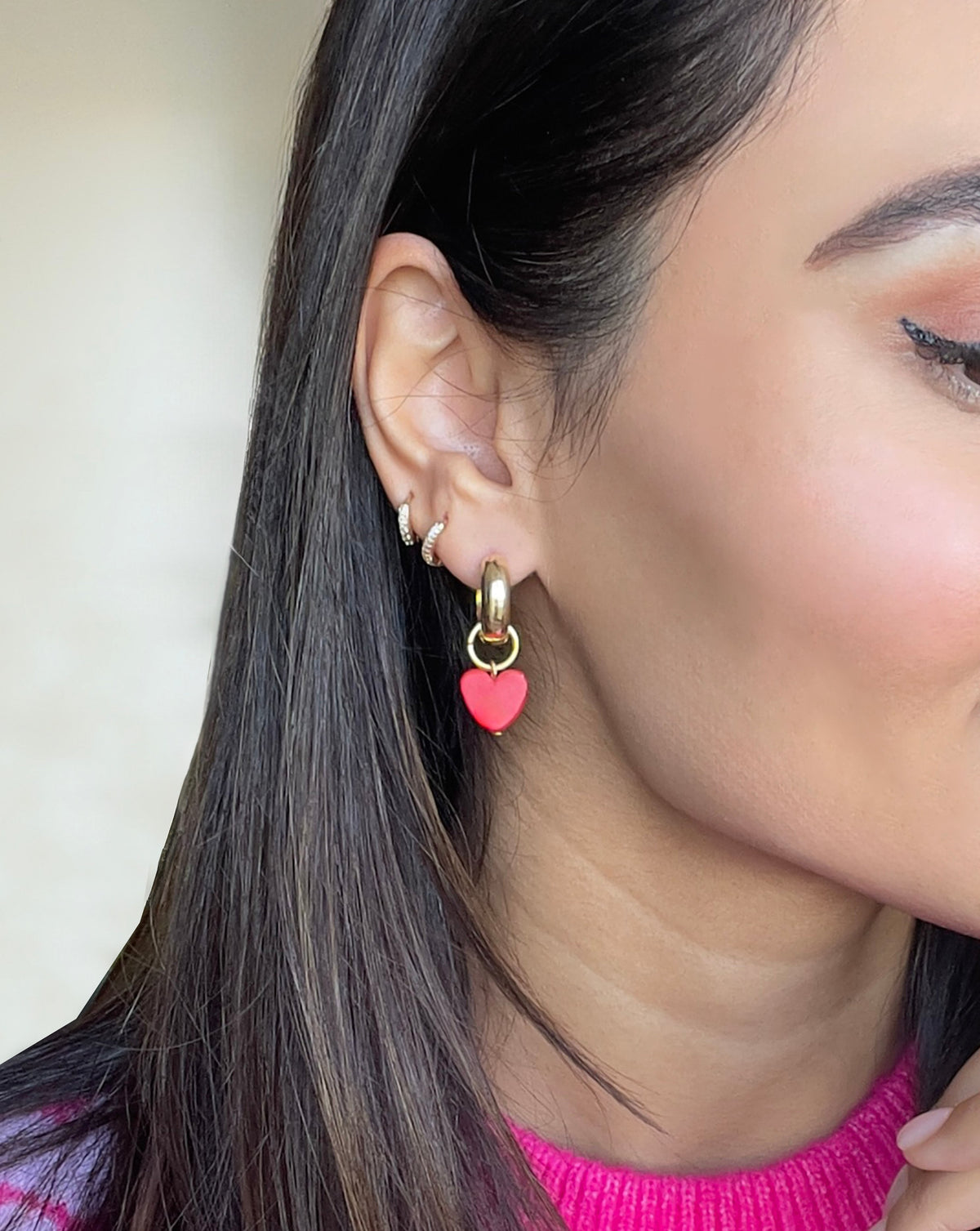 LYHO Charming heart earrings. Heart charm in color red with gold plated hoops on model.