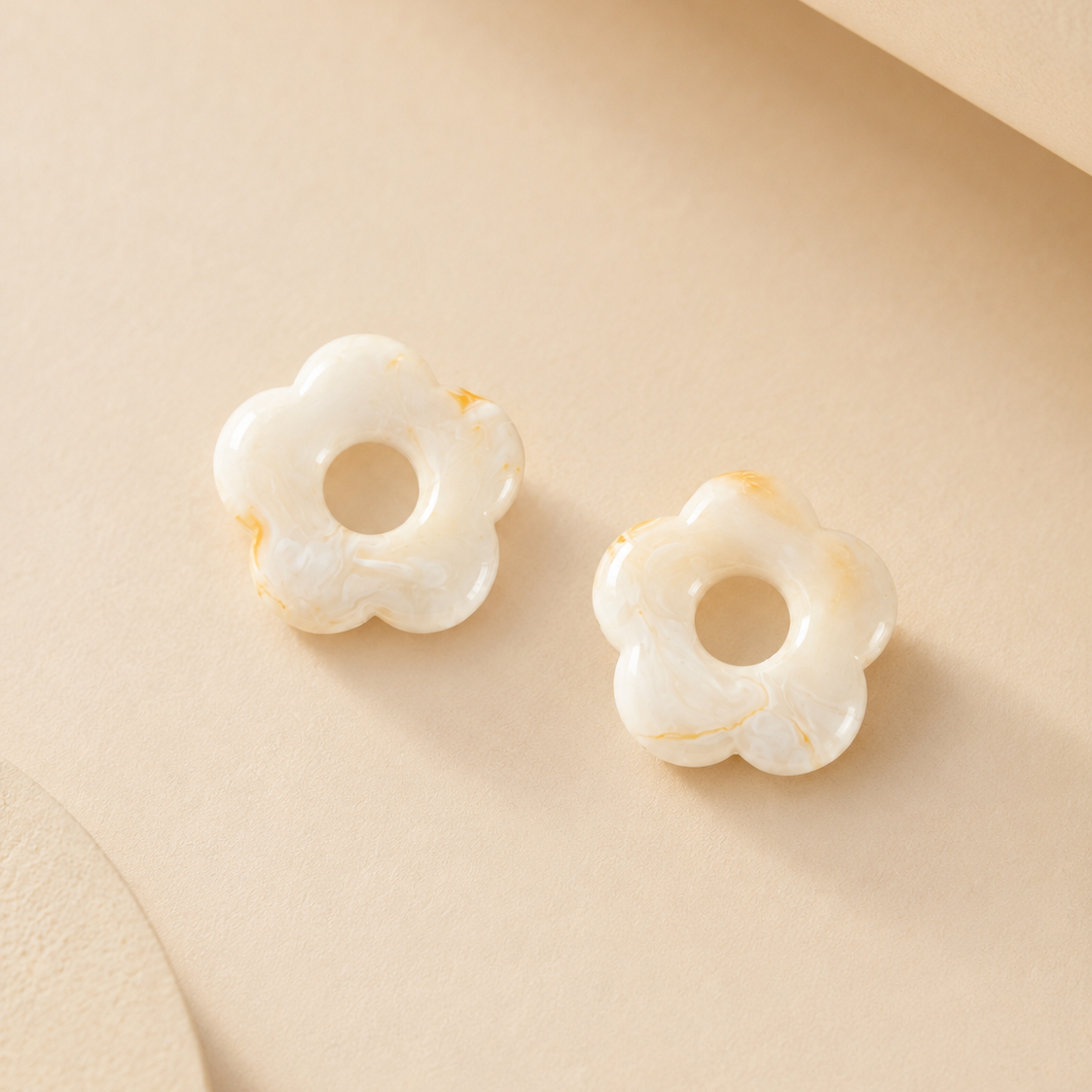 Pair of white floral earrings on a beige background