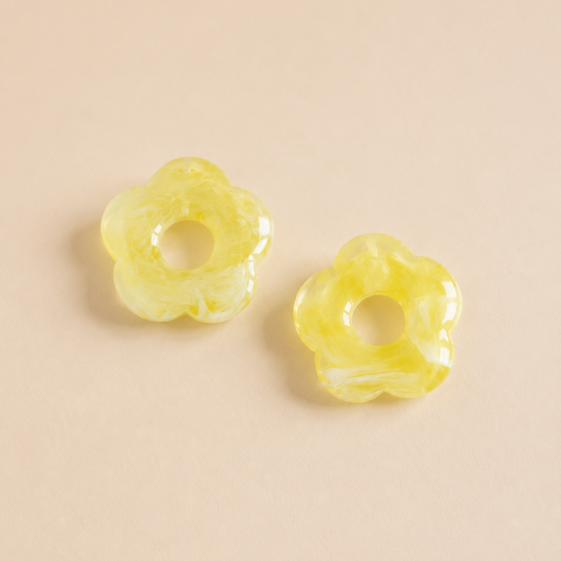 Two yellow floral earrings on a beige background