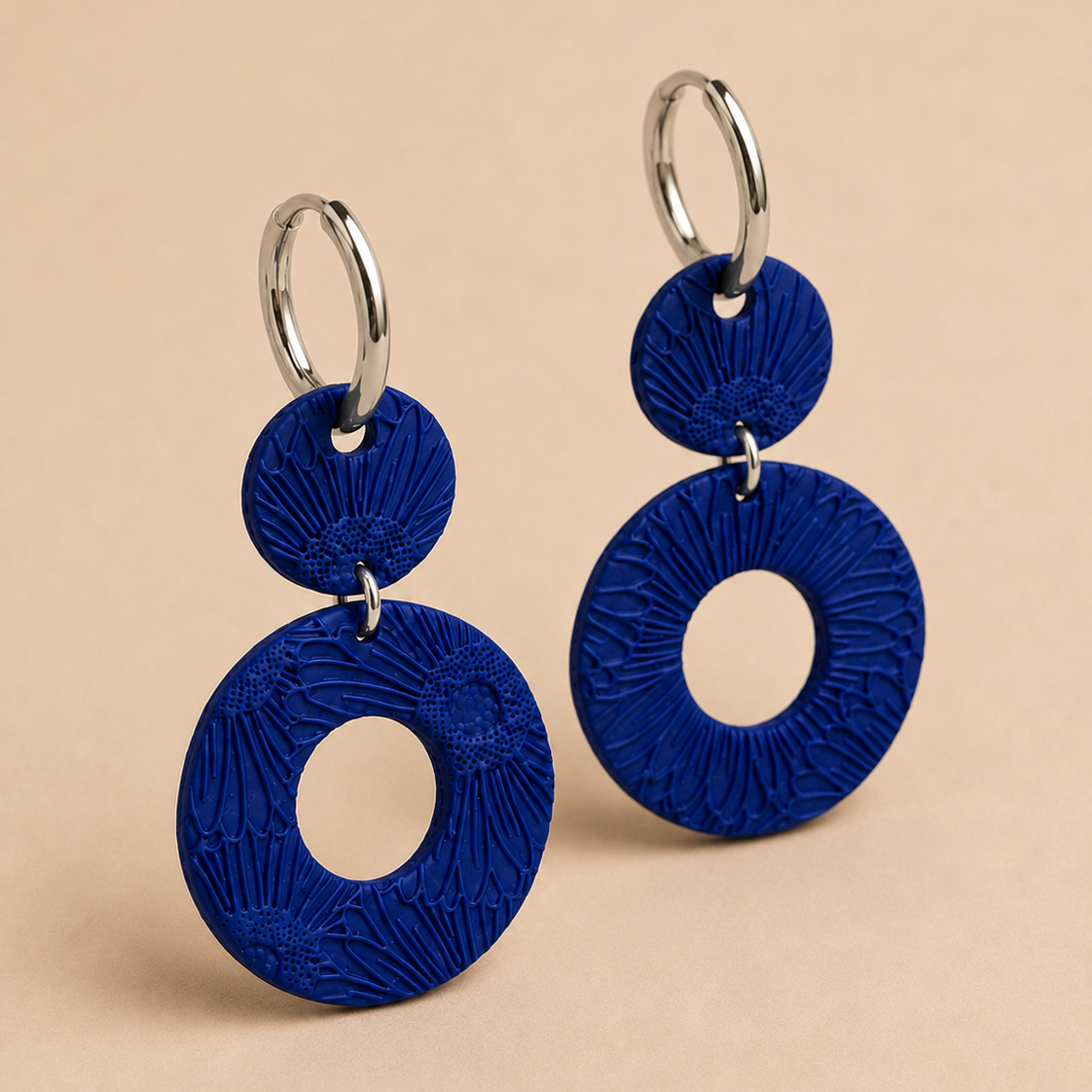 Blue earrings with circular design on a beige background