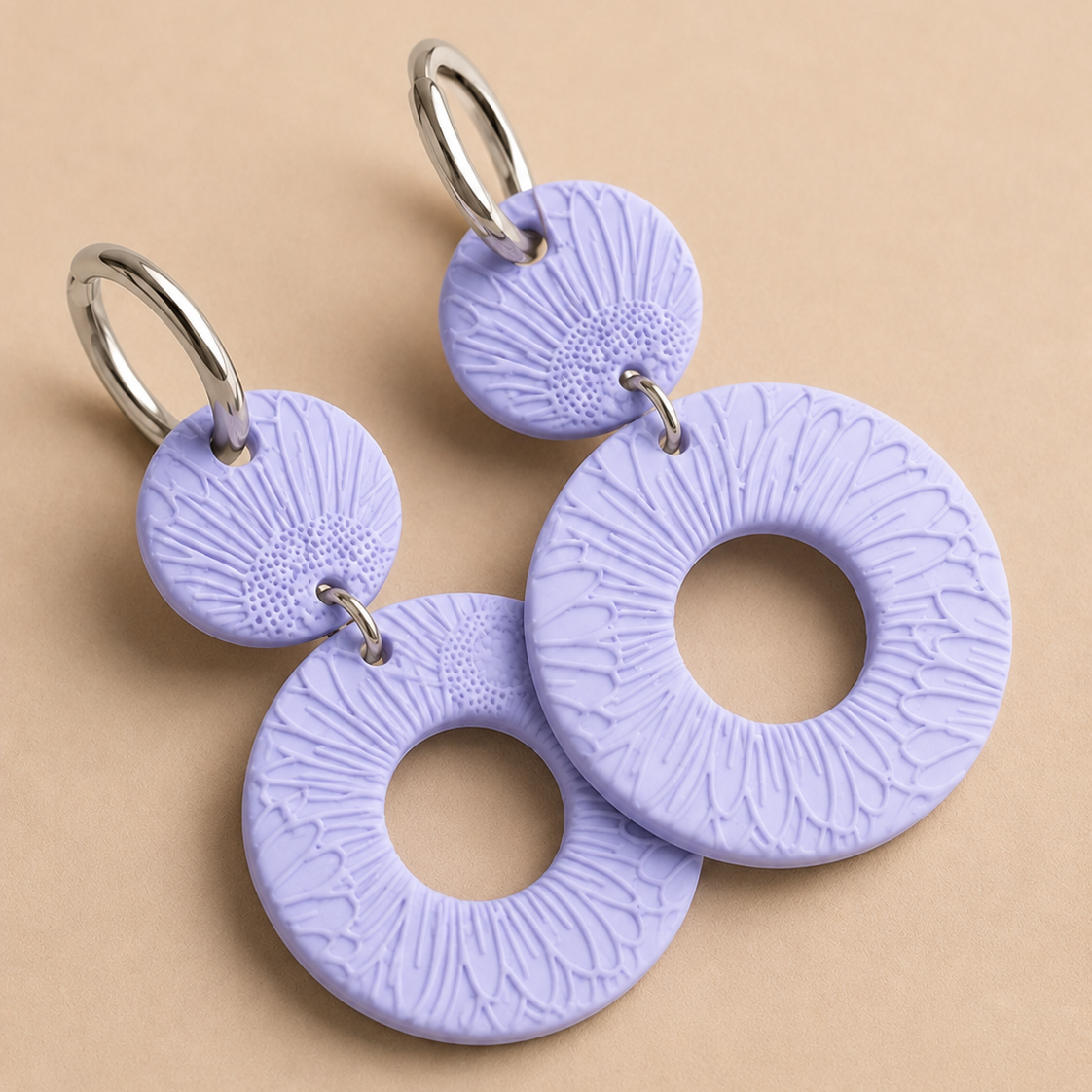 Pair of purple textured earrings on a beige background