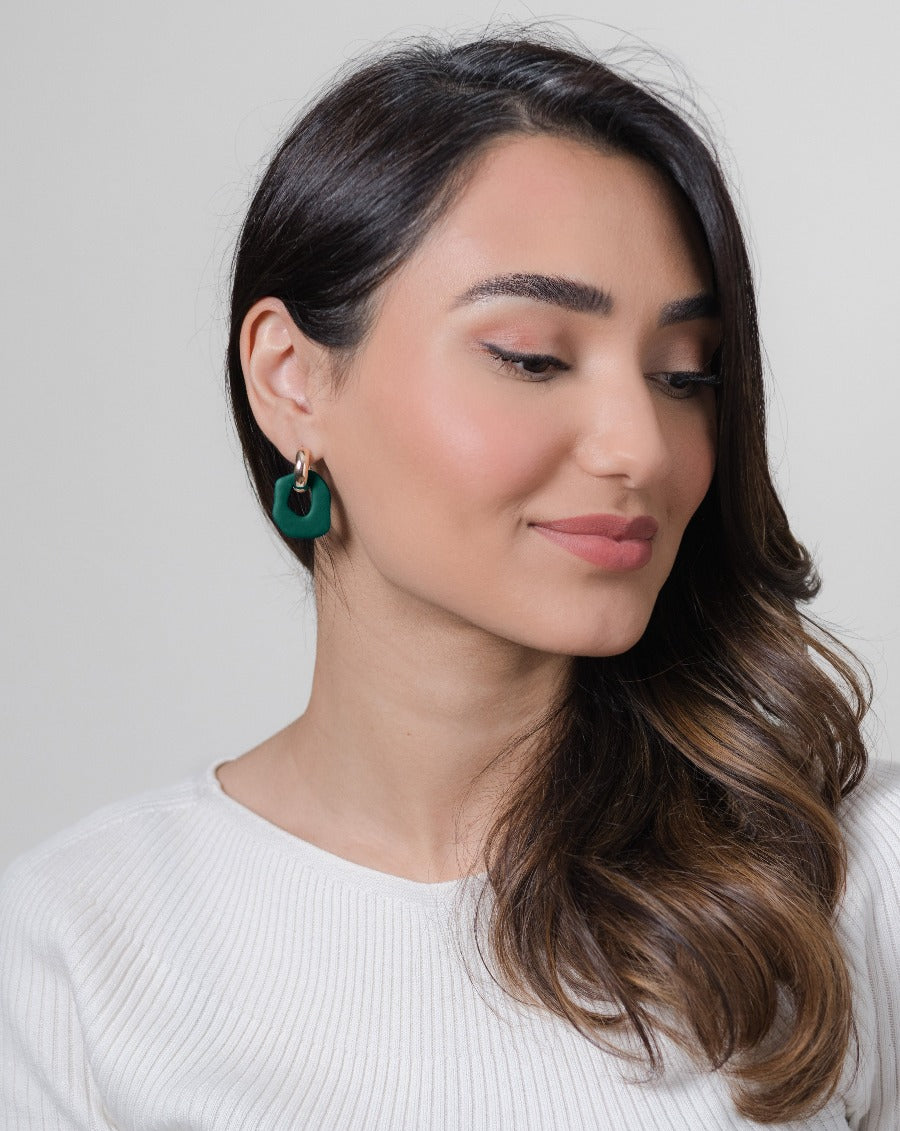 Close-up of Darien earrings in Pine with gold hoops, on model