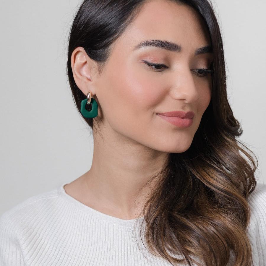 Close-up of Darien earrings in Pine with gold hoops, on model